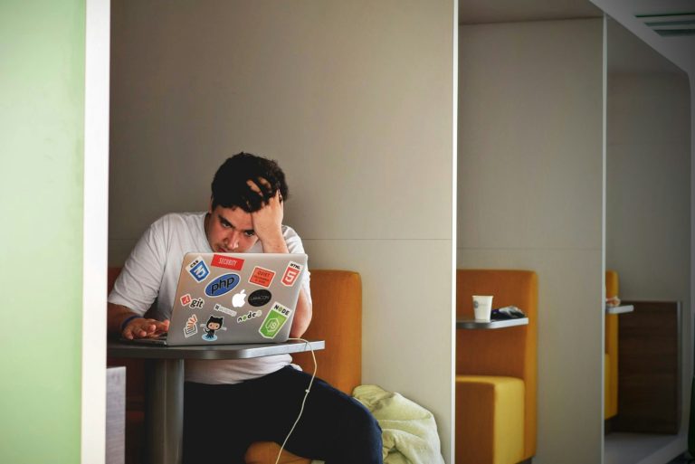 A man stares at his laptop looking bored and frustrated.