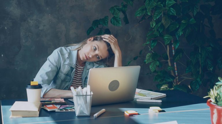 A woman stares at her laptop bored